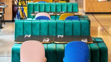 A seating area with green upholstered sofas and chairs, tables with cutlery, and a counter in the background.