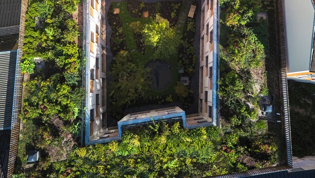 An aerial view of a modern building with a rooftop terrace featuring outdoor seating and a garden area. - Tribe Paris Clichy  (Clichy)