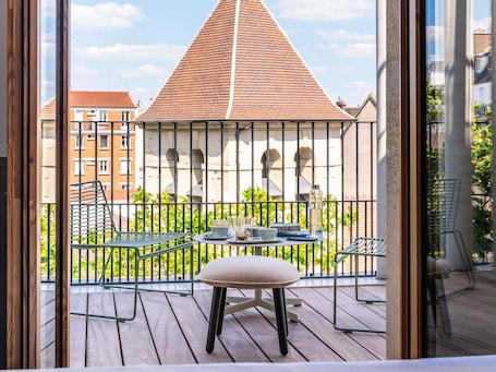 A balcony with a table, chairs, and a view of a building with a tiled roof.. Tribe Paris Clichy