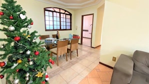 A dining area with a Christmas tree, a dining table with chairs, and a view into the kitchen.