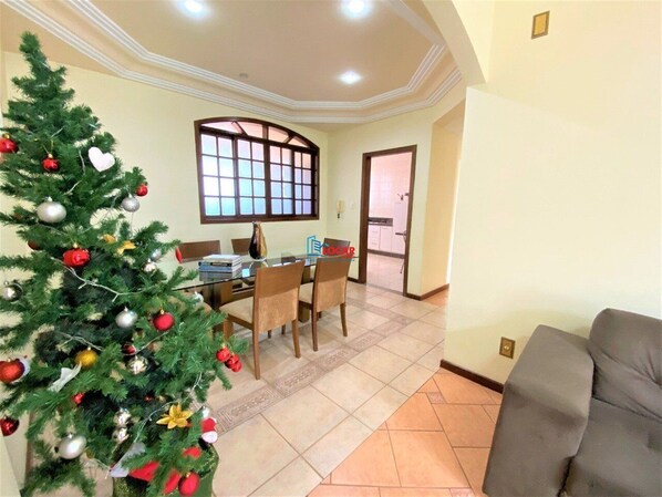 Un comedor con un árbol de Navidad, una mesa de comedor con sillas y vista a la cocina.