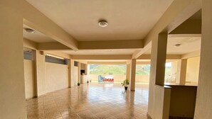 A spacious indoor area with a tiled floor and a view of hills in the distance.