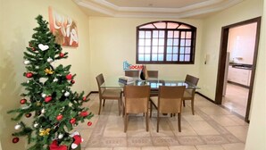 A dining area with a glass table and chairs, a Christmas tree, and a window with a view.