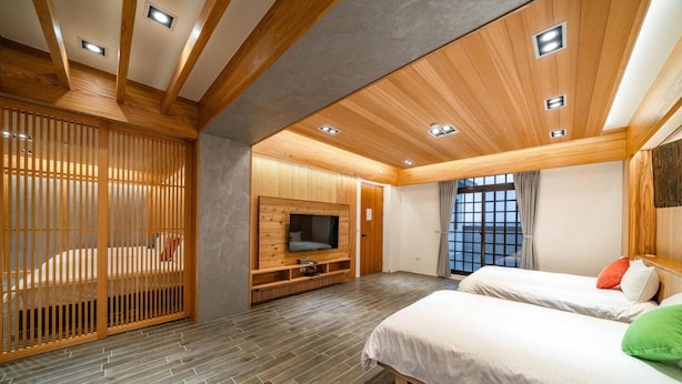 A modern bedroom with two beds, a TV, and a sliding wooden partition. - Young Villa (Wujie)