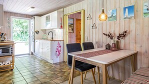 A cozy kitchen with a dining area, wooden walls, and a view of greenery outside. - 4 Person Holiday Home in Oksbol-by Traum (Oksbol)