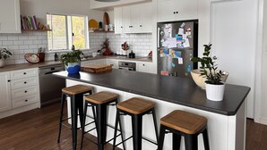 Una cocina moderna con armarios blancos, encimera negra y taburetes de madera.
