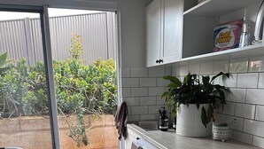 Una cocina compacta con lavadora incorporada, una planta en maceta y un salpicadero de azulejos.