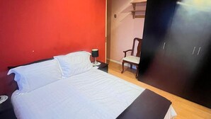 Een slaapkamer met een bed, nachtkastje, stoel en garderobe.
