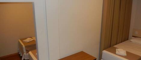 A hotel room with a single bed, a small table, a chair, and a desk.
