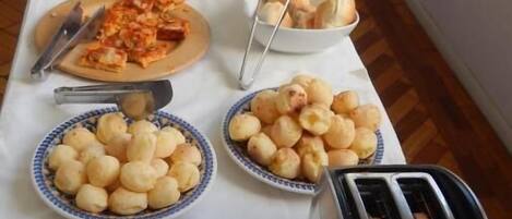 A buffet table with various food items including bread, pizza, and pastries.