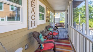 A covered porch with wicker chairs and a striped rug.
