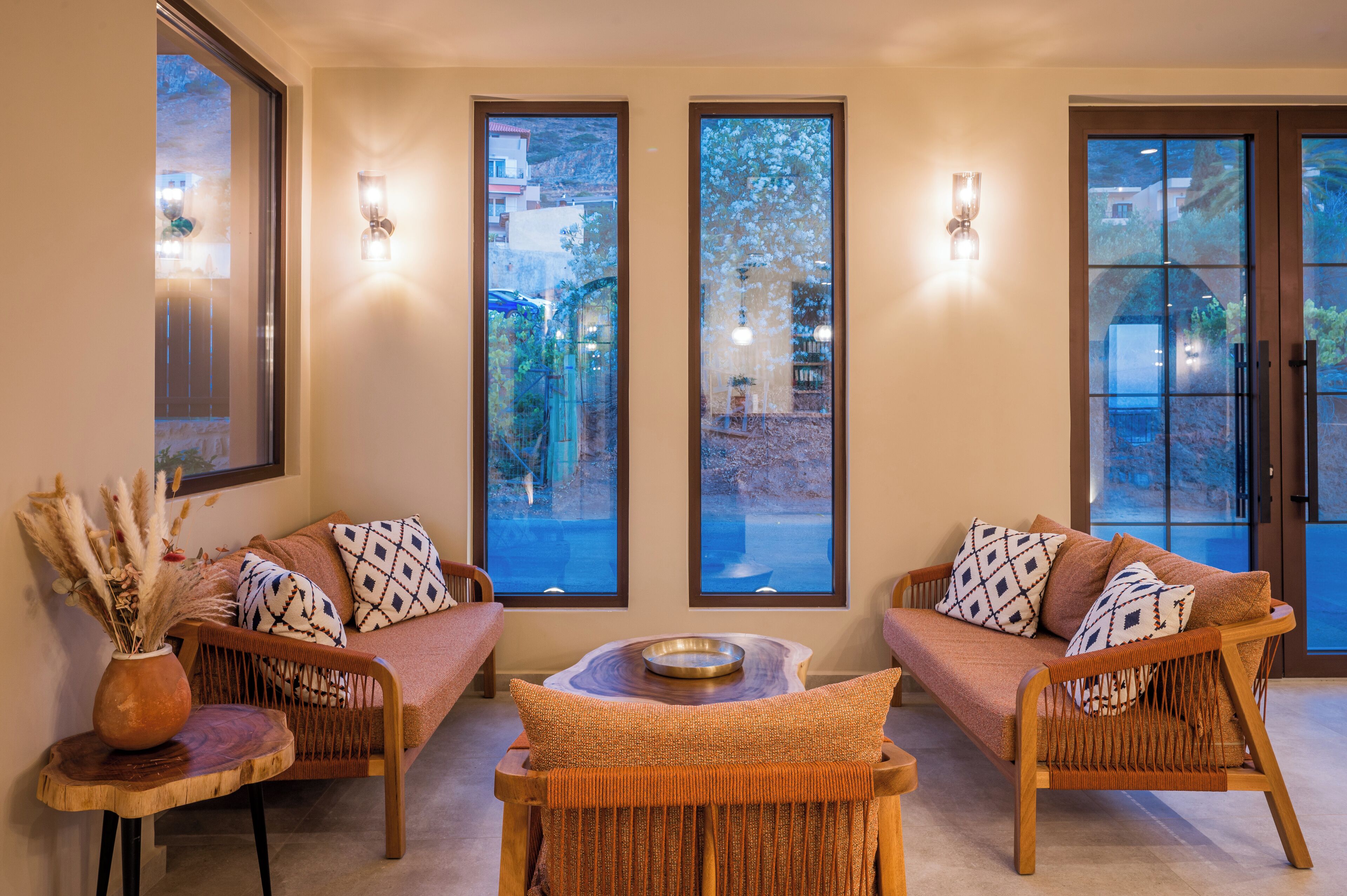 A cozy seating area with two wicker sofas, a small wooden table, and a vase of dried plants.