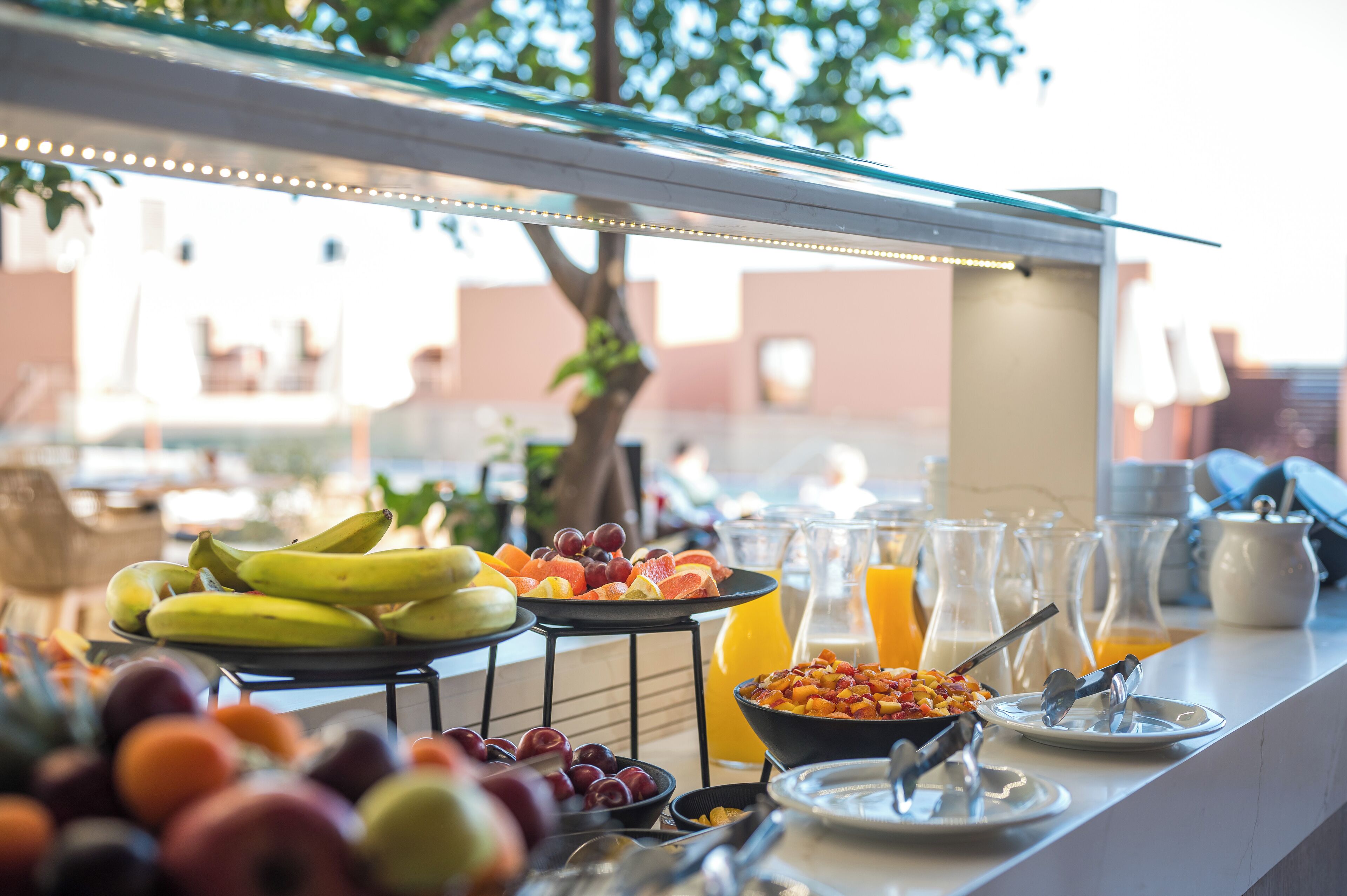 A breakfast buffet with fruits, cereals, and orange juice.