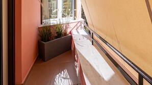 Ein Balkon mit einem Blumentopf, einem Fenster und einem Geländer.