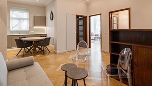 Ein modernes Wohnzimmer mit einer Couch, einem Esstisch mit Stühlen, einer Küchenzeile und einem Flur, der in einen anderen Raum führt.