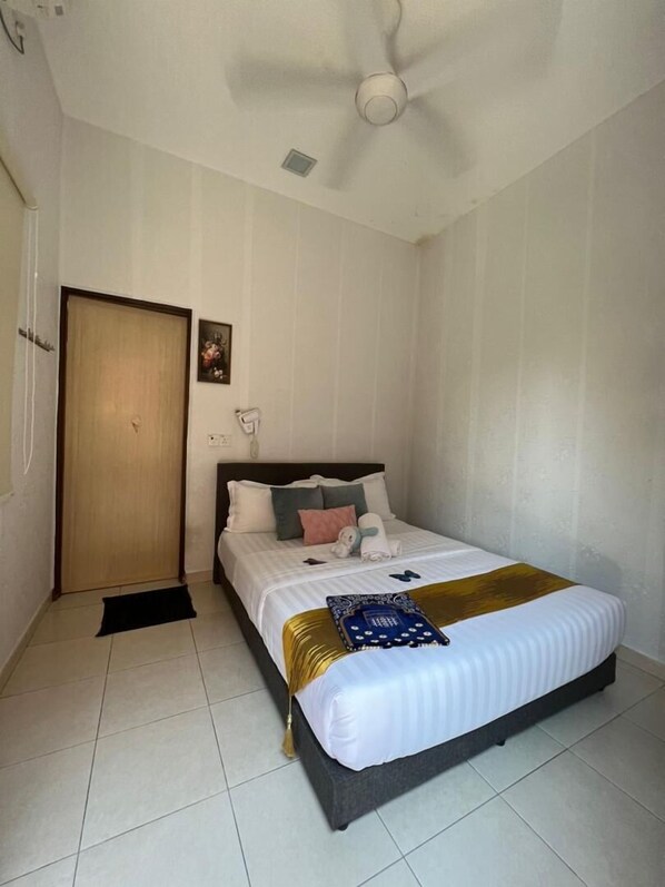 A neatly arranged bedroom with a bed, a ceiling fan, a door, and a small picture on the wall. - Sammy hoomesaty  (Ipoh)