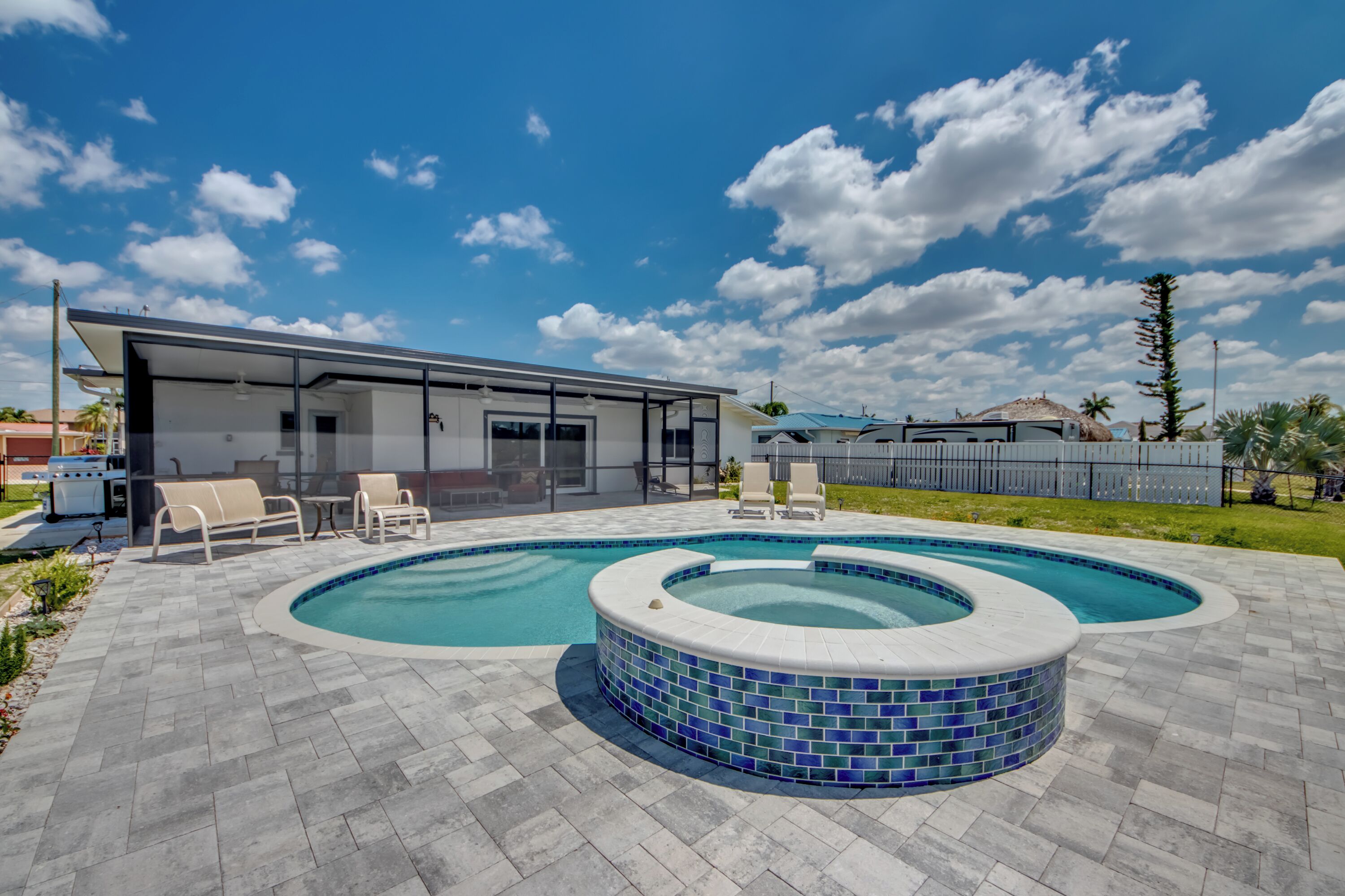 Ein modernes Haus mit Swimmingpool und Sitzgelegenheit im Freien.