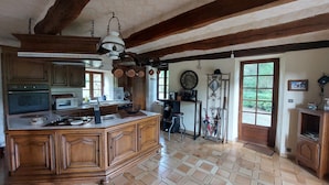 A spacious kitchen with a large island, wooden cabinets, and a tiled floor.