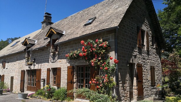 A stone building with a sloped roof, wooden shutters, and a flower box with red flowers. - la Longere du Haut Courby en Plein Cœur de la Forêt Domaniale de Sédières (Eyrein)