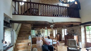 A spacious living area with a high ceiling, a staircase leading to an upper level, and a chandelier. - la Longere du Haut Courby en Plein Cœur de la Forêt Domaniale de Sédières (Eyrein)