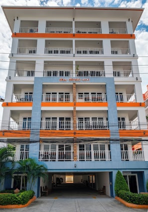 Un hotel de varios pisos con balcones, un estacionamiento y un letrero que dice 'New Hotel Club 3'.