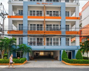 A multi-story hotel with balconies, a parking garage, and a pedestrian walkway. - New Nordic Club 3 by Apartwell (Pattaya)