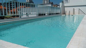 Une piscine à l’eau d’un bleu limpide, entourée d’une terrasse carrelée de blanc.