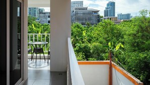 Un balcon avec une table et des chaises, offrant une vue sur le paysage urbain et une végétation luxuriante.