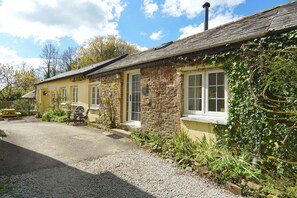 A rustic stone building with a gravel driveway and a picnic table. - 1 Bed 17th Century Stone Cottage in Rural Devon (Holsworthy)