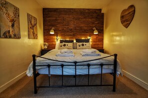 A bed with a metal frame, two pillows with animal prints, and a heart-shaped decoration on the wall. - 1 Bed 17th Century Stone Cottage in Rural Devon (Holsworthy)