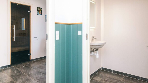 A hallway with a teal-colored door, a white sink, and a tiled floor. - 5 Star Holiday Home in Tarm (Tarm)