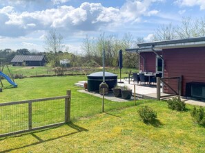 A fenced outdoor area with a hot tub, patio furniture, and a slide. - 5 Star Holiday Home in Tarm (Tarm)