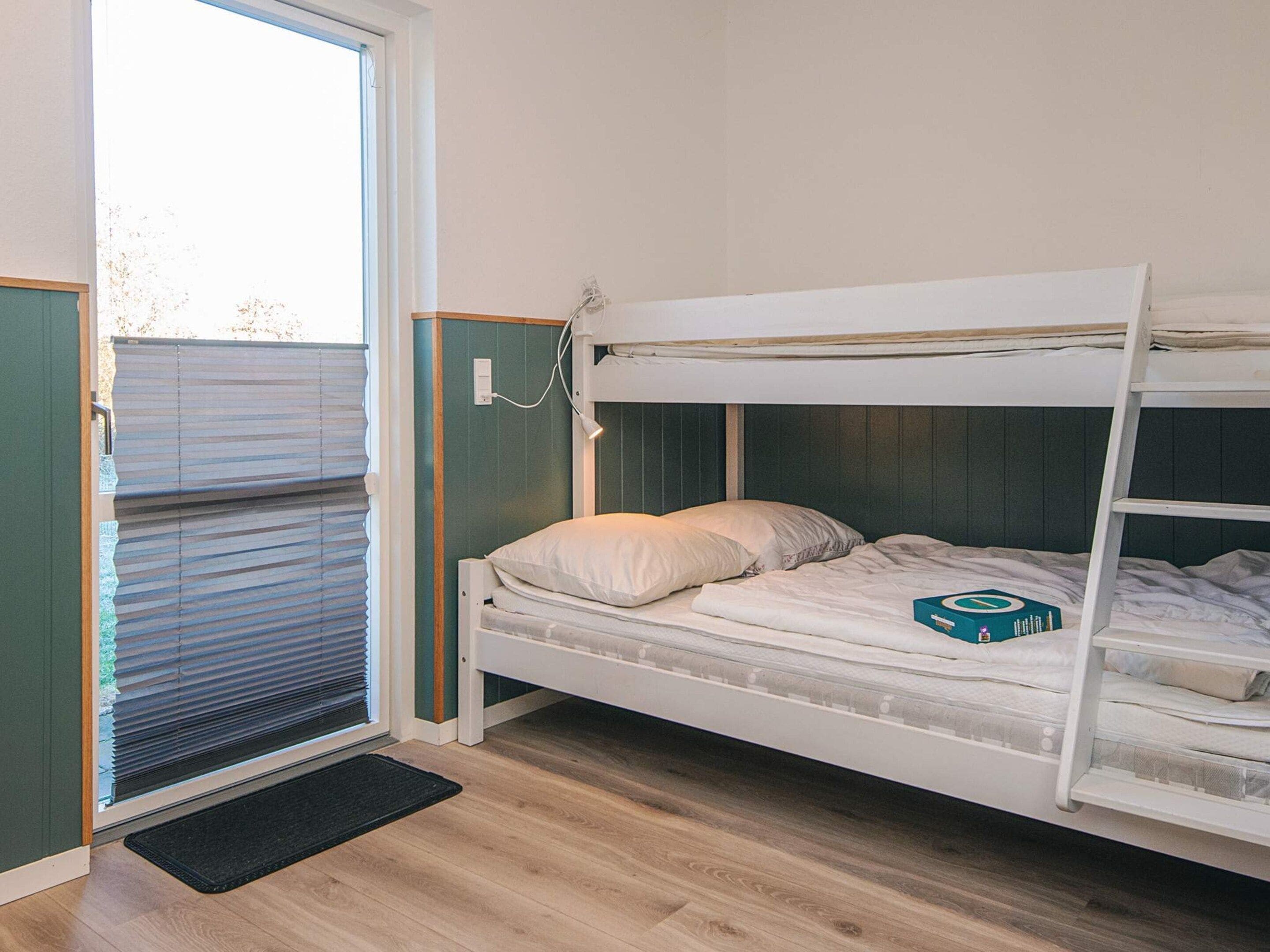 Habitación con literas, una ventana y un felpudo negro.