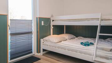 Habitación con literas, una ventana y un felpudo negro.