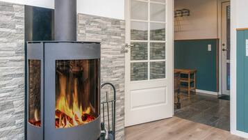 Una habitación moderna con chimenea de leña, pared de piedra y puerta que da a otra habitación.