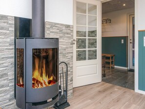 A modern room with a wood-burning stove, stone wall, and a door leading to another room.