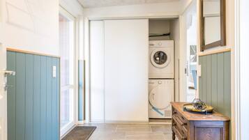 Un lavadero con lavadora y secadora, un armario de madera y una puerta que da a otra habitación.