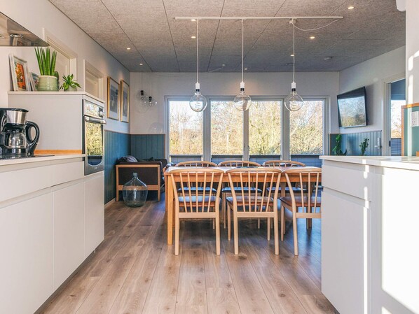 A modern kitchen with wooden chairs, a coffee machine, and a large window.