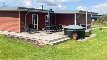 Una casa moderna con terraza, mobiliario exterior y jacuzzi.
