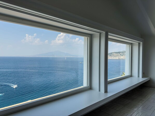 A room with large windows overlooking a coastal view, including a distant mountain and sea. - Grand Hotel Europa Palace (Sorrento)