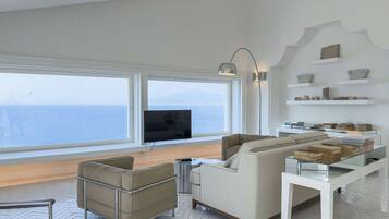 Uma sala de estar moderna com sofá, poltrona e mesa de centro de vidro.