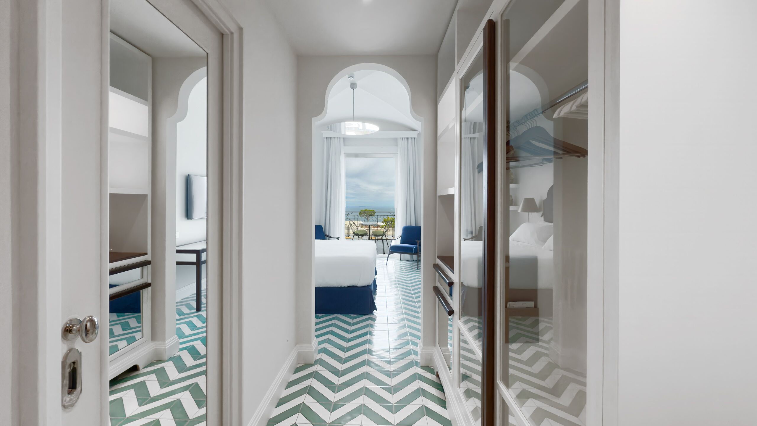 Un couloir d’hôtel avec un lit, des chaises et une vue sur la mer.