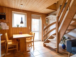 A wooden interior with a dining area, a staircase, and a window.