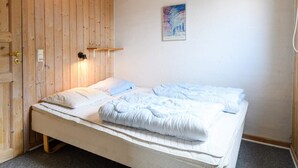 A single bed with a white mattress and blue bedding, a wooden door, a wall-mounted light, and a framed picture. - 4 Person Holiday Home in Fano (Fano)