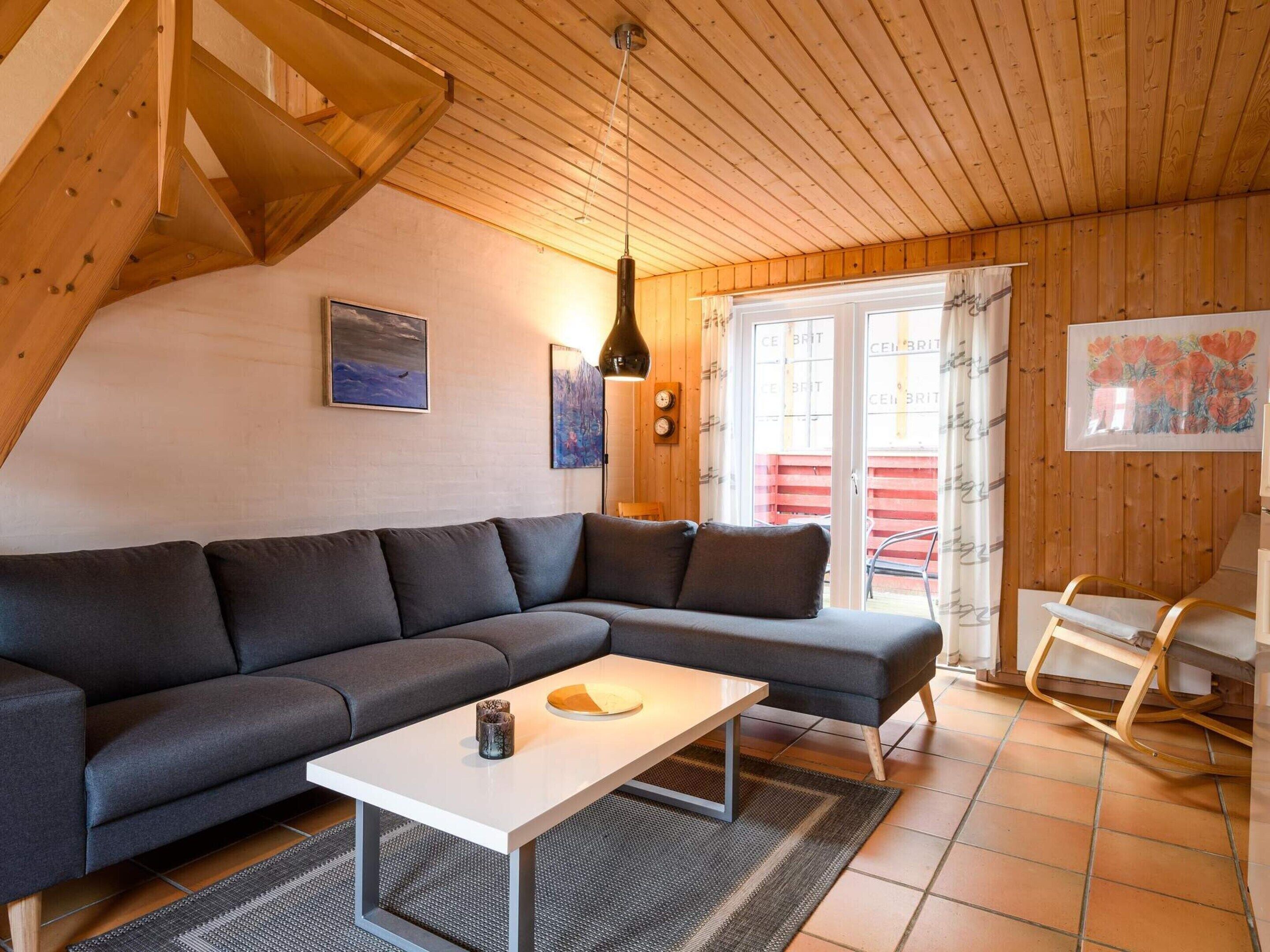 A modern living room with a sectional sofa, a coffee table, and a wooden ceiling.