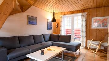 A modern living room with a sectional sofa, a coffee table, and a wooden ceiling.