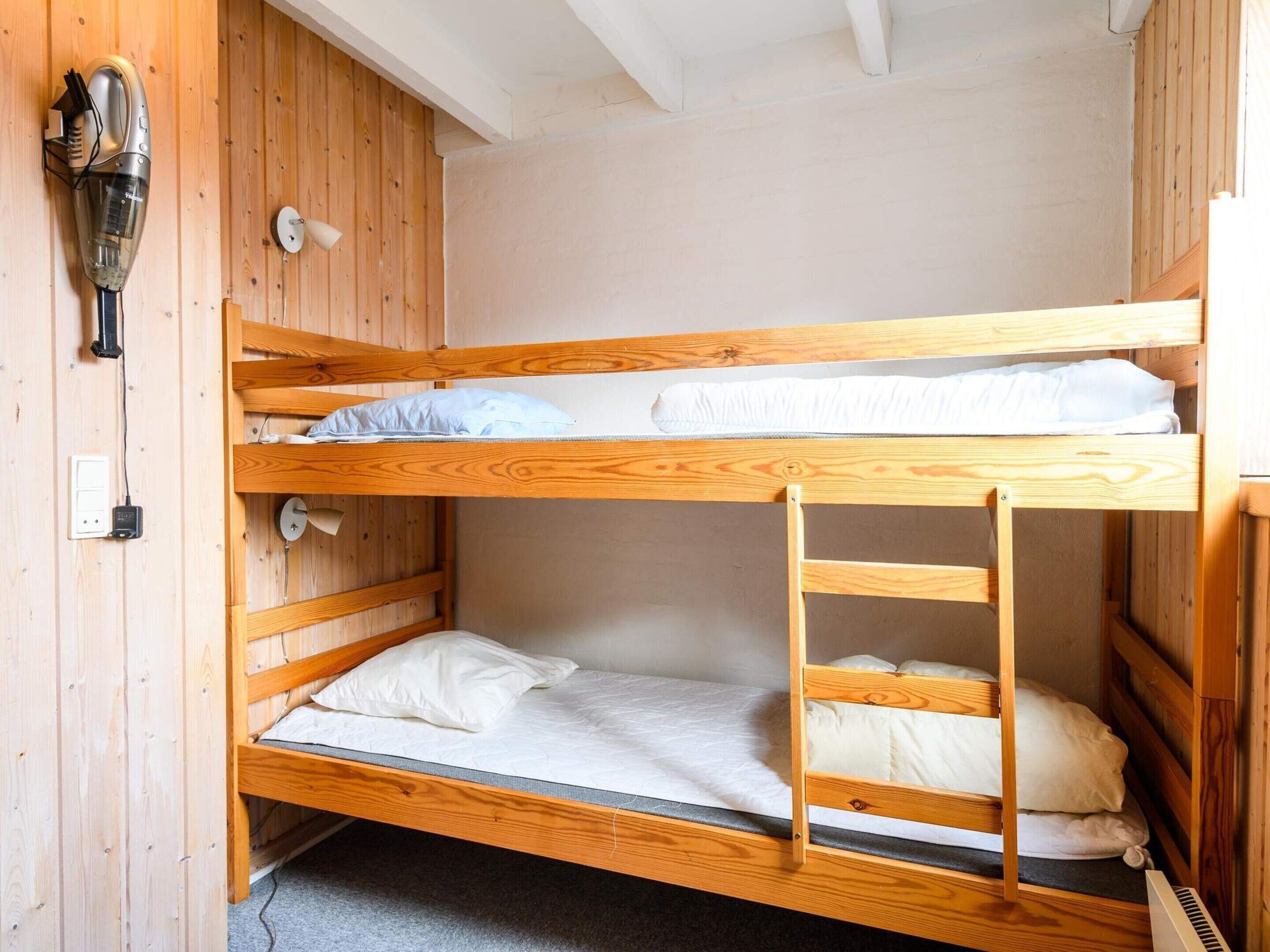 Habitació amb lliteres, interior de fusta, un assecador i una presa elèctrica.