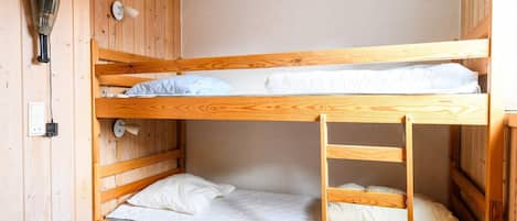 A bunk bed room with a wooden interior, a hairdryer, and a power outlet.