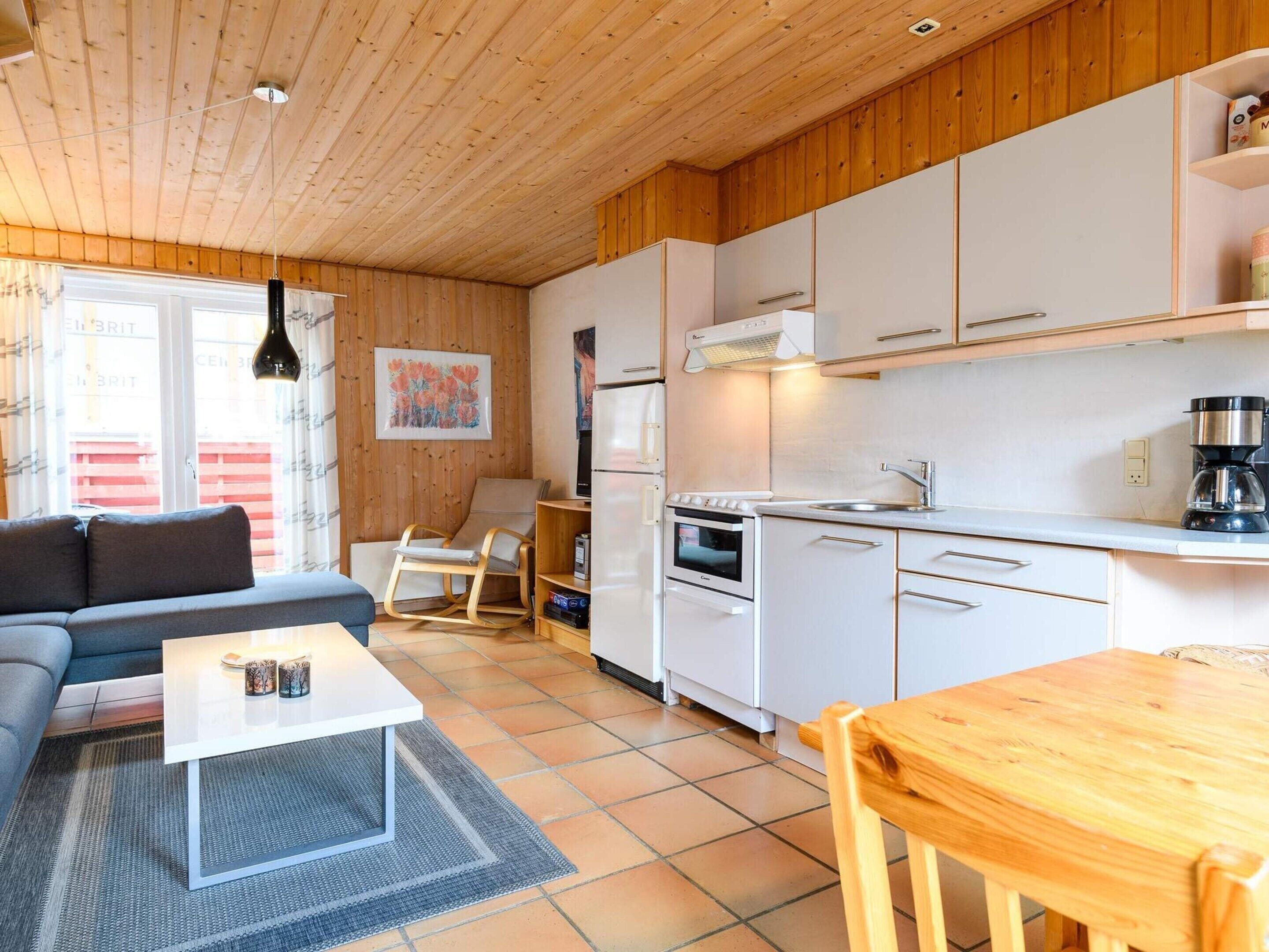 Un espacio habitable compacto con kitchenette, un sofá, una mesa de comedor y una mecedora.