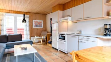 Un espacio habitable compacto con kitchenette, un sofá, una mesa de comedor y una mecedora.